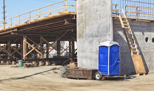 blue portable toilets arranged in a neat line on a job site